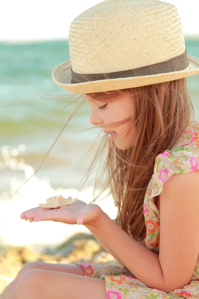 Leende liten flicka håller en sjöstjärna på handen vid havet. — Stockfoto