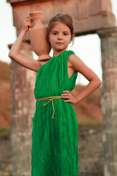 Adorable little girl in a beautiful dress with a vintage antique amphora. — Stock Photo, Image