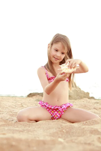 sahilde oturup pembe bir mayo mutlu beyaz genç kız.