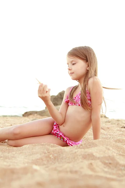 Charmig flicka i rosa baddräkt håller seashell vid Svarta havet. — Stockfoto