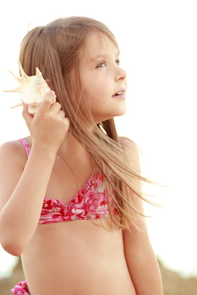 Charmig flicka i rosa baddräkt håller seashell vid Svarta havet. — Stockfoto
