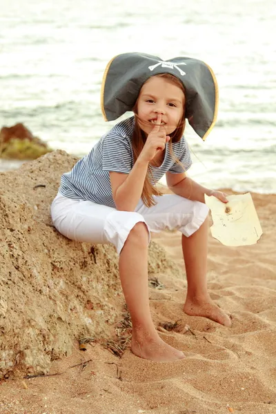 Bela menina alegre em um traje de pirata está estudando um mapa do tesouro . — Fotografia de Stock