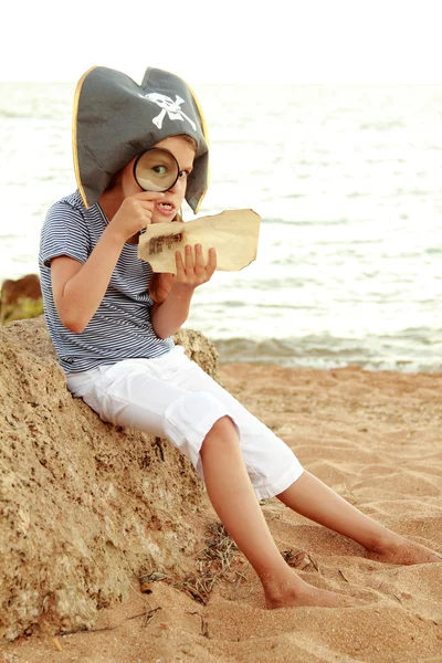 Bella allegra bambina in costume da pirata sta studiando una mappa del tesoro . — Foto Stock