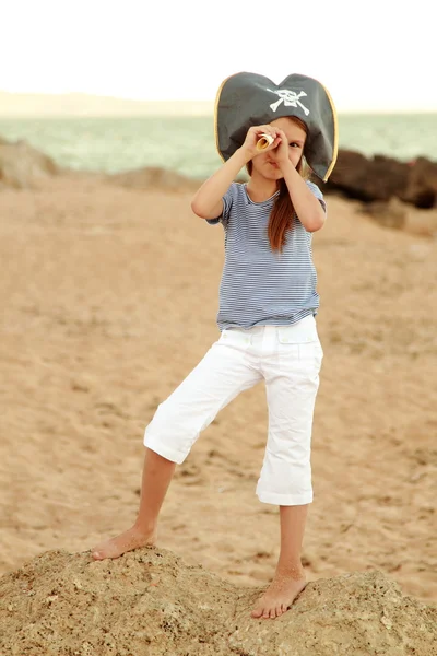 Caucasian emotional little girl in a hat with a symbol of maritime piracy. — Stock Photo, Image