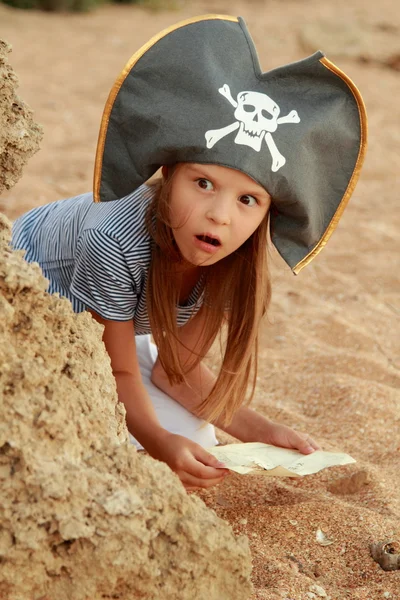 Emotional young girl in a pirate hat is angry and looking for treasure on the beach. — Stock Photo, Image