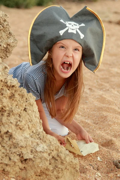 Emotional young girl in a pirate hat is angry and looking for treasure on the beach. — Stock Photo, Image