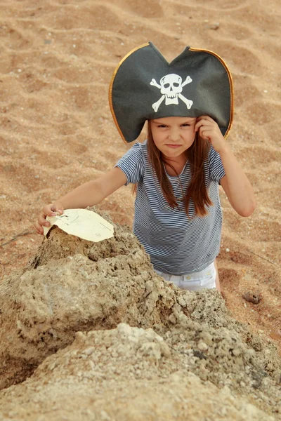 Bella bambina in costume da pirata con un sorriso malvagio sta tenendo una mappa . — Foto Stock