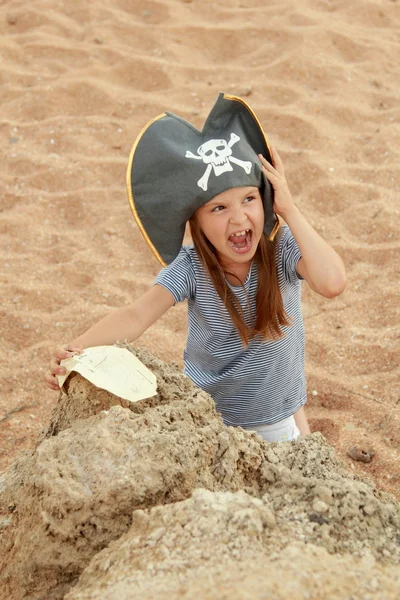 Bella bambina in costume da pirata con un sorriso malvagio sta tenendo una mappa . — Foto Stock