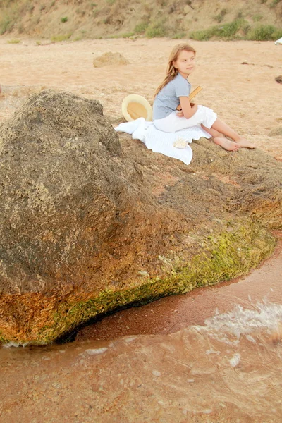 Kaukasisch lächelndes junges Mädchen in lässiger Kleidung liest an einem Sommertag ein Buch am Strand. — Stockfoto