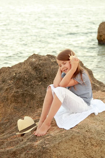 Olumlu bir yazlık elbise, gülümseyen küçük kız Karadeniz sahilinde günbatımında oynanır. — Stok fotoğraf