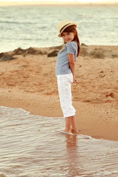 Olumlu bir yazlık elbise, gülümseyen küçük kız Karadeniz sahilinde günbatımında oynanır. — Stok fotoğraf