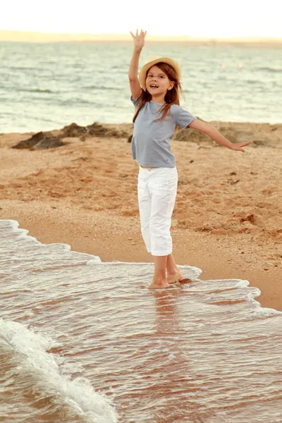 Okouzlující veselá holčička v létě klobouku usmívá a pózuje pro letní moře. — Stock fotografie
