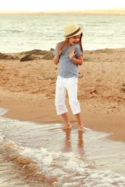 Positivo sorridente bambina in un abito estivo si gioca sulla costa del Mar Nero al tramonto . — Foto Stock