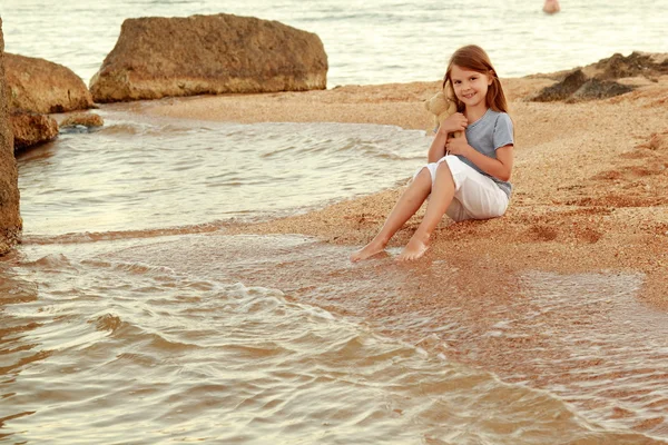 Känslomässiga glada unga flickan promenerar på stranden vid solnedgången. — Stockfoto