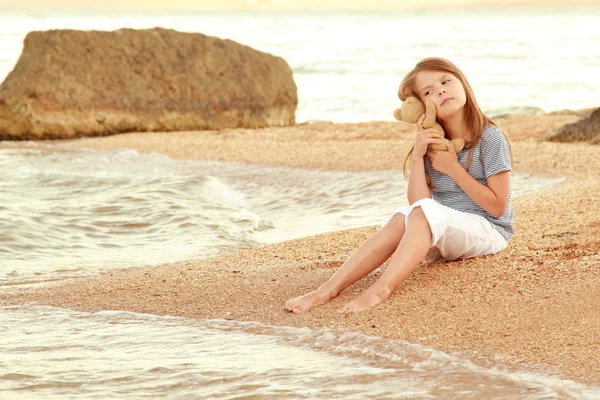 Positiva leende liten flicka i en sommarklänning spelas upp på Svarta havets kust i solnedgången. — Stockfoto
