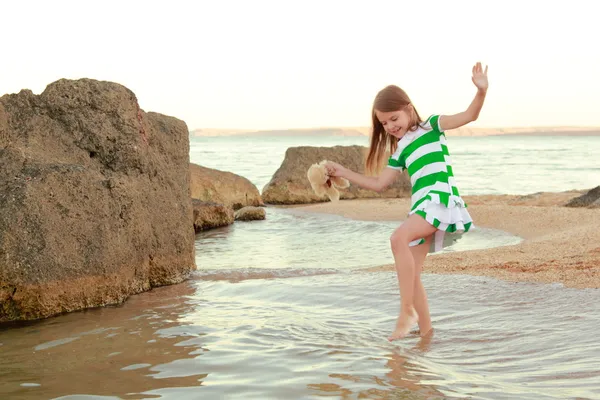 Jovem menina alegre emocional andando na praia ao pôr do sol . — Fotografia de Stock