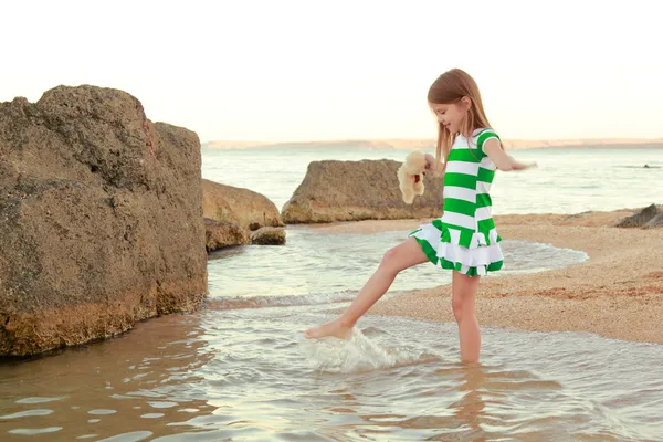 Positiva niña sonriente en un vestido de verano se juega en la costa del Mar Negro al atardecer —  Fotos de Stock