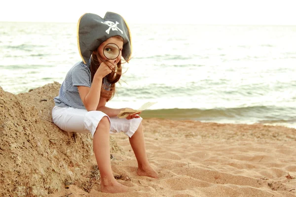 Caucásico niña emocional en un sombrero con un símbolo de la piratería marítima mantiene — Foto de Stock