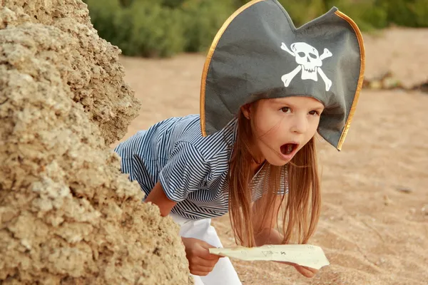 Mooi meisje in een piraat kostuum met een boze grijns houdt een kaart — Stockfoto