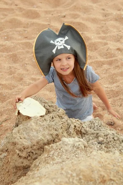 Menina bonita em um traje de pirata com um sorriso perverso está segurando um mapa — Fotografia de Stock