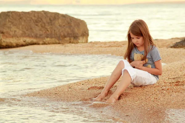 Positieve lachende meisje in een zomerjurk wordt gespeeld op de kust van de Zwarte Zee bij zonsondergang — Stockfoto