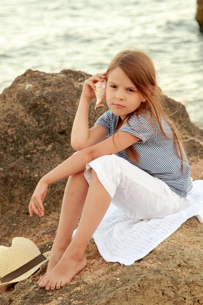 Positive smiling little girl in a summer dress is played on the Black Sea coast at sunset — Stock Photo, Image