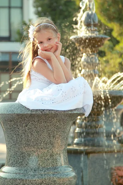 Caucásico precioso sonriente niña cerca de la fuente en sammer — Foto de Stock