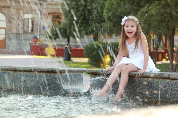 Freudiges junges Mädchen mit schönem Haar nass Füße in einem Brunnen an einem heißen Sommertag — Stockfoto