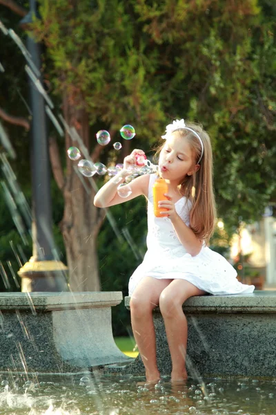 Caucasian happy young girl with beautiful hair and a sweet smile blow bubbles — Stock Photo, Image