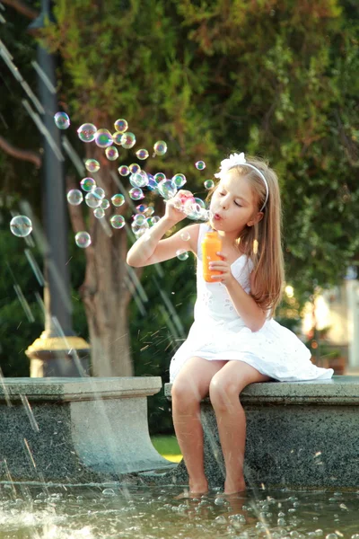 Malá holčička baví hrát a užívat si sprej fontány na horký den — Stock fotografie