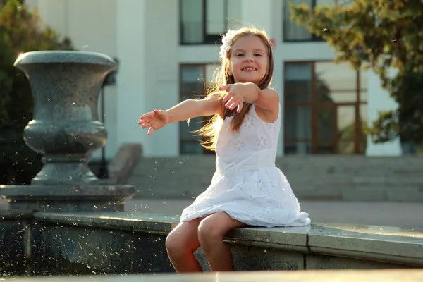 Petite fille jouer et avoir du plaisir à profiter de la pulvérisation de la fontaine par une journée chaude en plein air — Photo