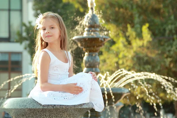Bedårande söt liten flicka leende och poserar nära fontänen på sommaren utomhus — Stockfoto