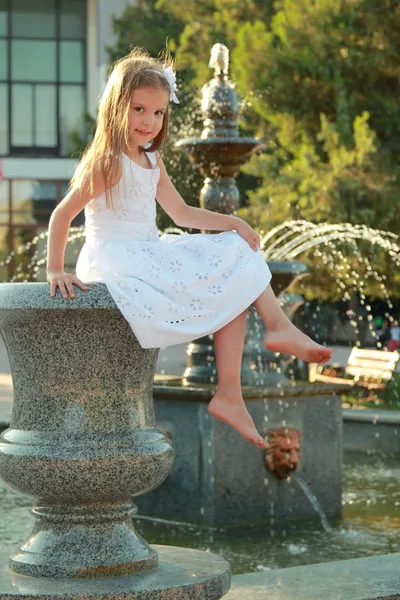 Bedårande söt liten flicka leende och poserar nära fontänen på sommaren utomhus — Stockfoto