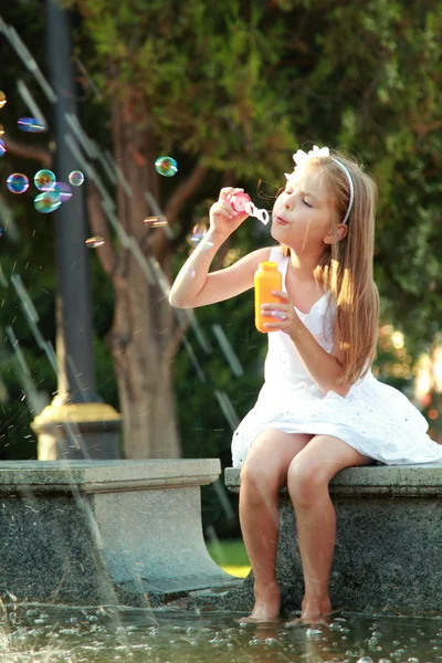 Caucasian happy young girl with beautiful hair and a sweet smile blow bubbles — Stock Photo, Image