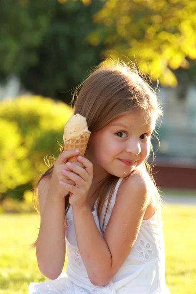 Красивая маленькая девочка ест мороженое на открытом воздухе — стоковое фото