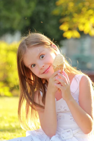 Glücklich niedliches kleines Mädchen in lässiger Kleidung essen Eis auf einem Hintergrund der Natur im Sommer — Stockfoto