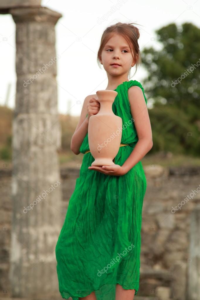 Charming girl in the emerald dress holding ancient amphora on the excavation of ancient city Pantikapaion.