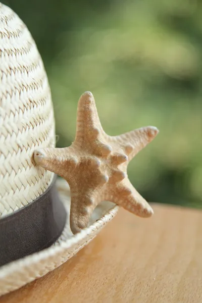 Sombrero de paja y estrella de mar sobre fondo de madera — Foto de Stock