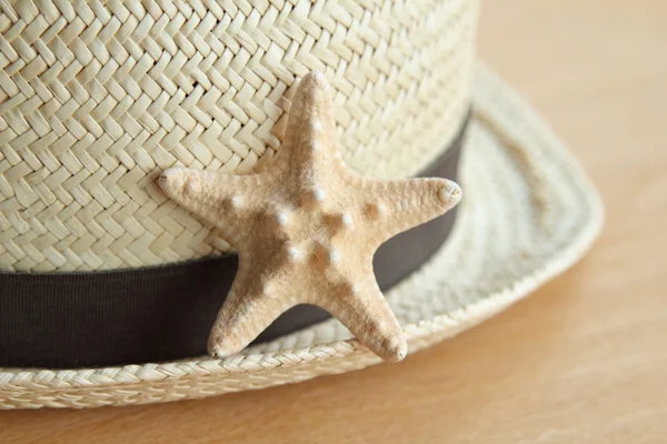 Summer straw hat and a little starfish wooden background — Stock Photo, Image