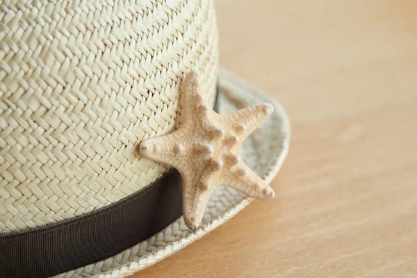 Summer straw hat and a little starfish wooden background — Stock Photo, Image
