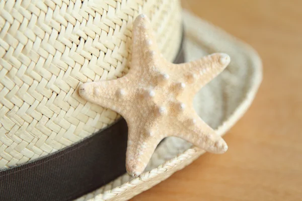 Sombrero de paja y estrella de mar sobre fondo de madera — Foto de Stock