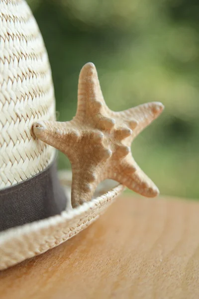 Straw hat and a little starfish blurred background — Stock Photo, Image