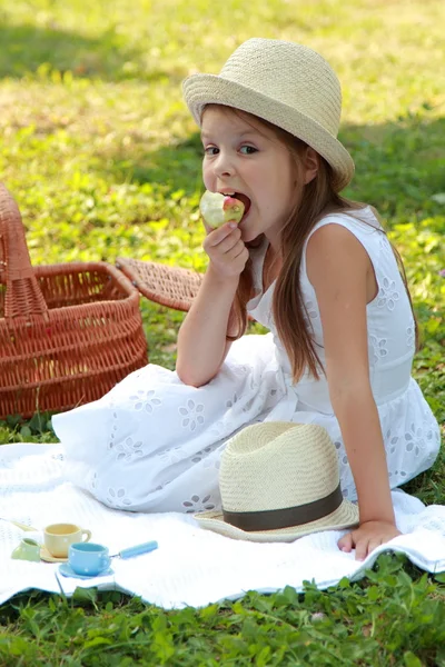 Girl eats an apple in a summer day — Stock Photo, Image