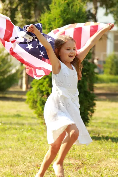 Chica sosteniendo una gran bandera americana — Foto de Stock