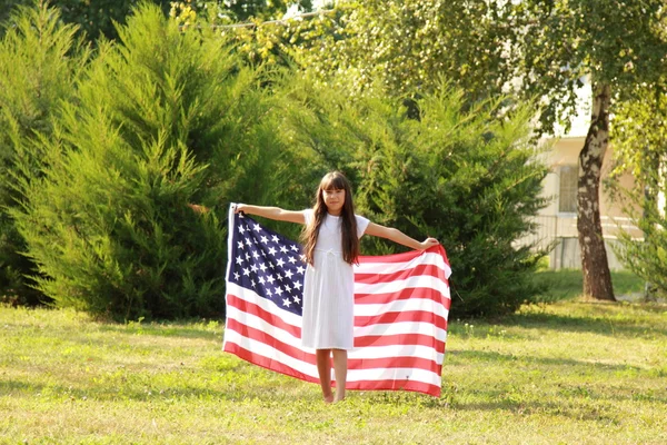 Fille tenant un grand drapeau américain — Photo