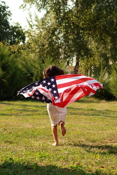 Fille tenant un grand drapeau américain — Photo