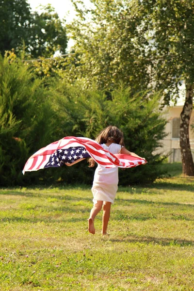 Flicka som håller en stor amerikansk flagga — Stockfoto