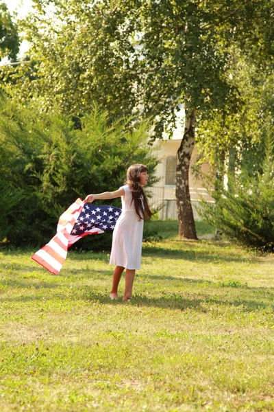 Flicka som håller en stor amerikansk flagga — Stockfoto