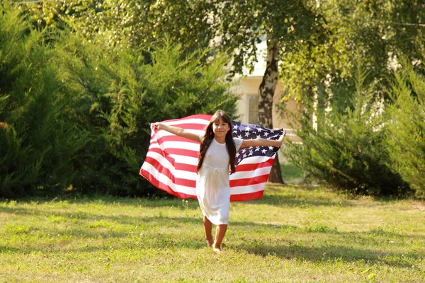 Chica sosteniendo una gran bandera americana — Foto de Stock