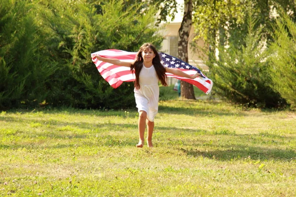 Menina segurando uma grande bandeira americana — Fotografia de Stock